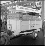 7570-2 Boeren uit Flakkee op hun met aardappelkisten volgeladen aanhanger, delen zakjes met 2 kilo aardappelen uit aan ...