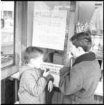7695 Twee jongens eten producten van een snackkar; naast handgeschreven- en waarschuwende verwijzing naar ...