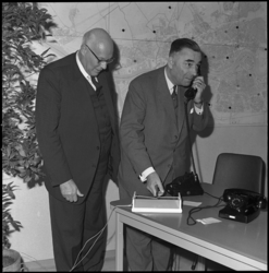 7970-2 Ingenieur R. Diks, hoofddirecteur Telegrafie en Telefonie, knipt -met telefoonhoorn aan het oor- als ...