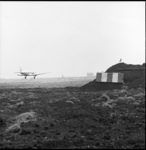 8124 Grondwerkzaamheden op vliegveld Zestienhoven in verband met uitbreiding; en landend vliegtuig boven de landingsbaan.
