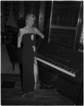 877-2 Model in avondkleding, bij piano tijdens modeshow van Waagemans.