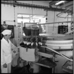8936 Werknemer staat naast machine tijdens de productie van ijsjes bij de Nederlandse Melk Unie.