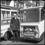 9031 Melkboer viert veertigjarig jubileum; staat voor zijn gemotoriseerde melkwagen.