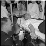 916 Door een collega van USS Robert K. Huntington'' wordt bloed afgenomen bij een man op een brancard.