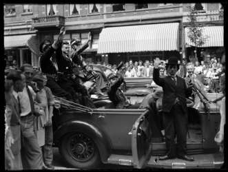 R-1916 Een imitatie van Charley Chaplin brengt, samen met andere acteurs, de Hitler-groet. De wagen waarmee zij rijden ...