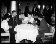 R-1919 Zangeres Heintje Davids zit in een restaurant aan tafel met haar man Philip Pinkhof en gasten.
