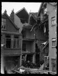 R-1956 Mannen ruimen puin bij een woonhuis dat zwaar is beschadigd na een bominslag.