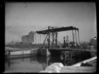 R-1975 Ophaalbrug de Pakkenbrug over de Nieuwe Haven. Achter de brug ligt een stoomboot. Op de achtergrond worden ...