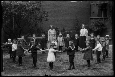 R-4917 Kleuterschool Vredenoord aan de Bethlehemstraat in Kralingen. Kinderen en leidsters staan op een binnenplaats ...
