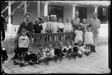 R-4920 Kleuterschool Vredenoord aan de Bethlehemstraat in Kralingen. Kinderen poseren met leidsters voor de school. ...