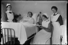 R-4927 Drie verpleegsters staan in het Eudokiaziekenhuis bij het bed van een patiënt.