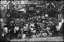 R-4931 Op Koninginnedag poseert een grote groep kinderen in een versierde Isaäc Hubertstraat. Sommige kinderen zijn verkleed.