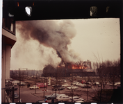 2003-905-58 Een gebouw in brand. Op de voorgrond geparkeerde auto's.