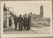 WN-112 Een groepje mannen staat naast spoorviaduct. Rechts het gebied tussen de Meent en het Grotekerkplein. Op de ...