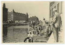 WN-184 Jongens en meisjes zitten in zomerse kleding en ook zwemkleding op een aflopende trap naar de Delftsevaart. Een ...