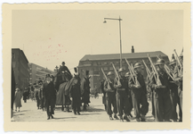 WN-7 Een militaire begrafenis. Over de Meent marcheren marechaussees gevolgd door begrafeniskoetsen met paarden. Rechts ...