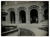XII-52-03 Twee mannen staan onder één van de bogen op de binnenplaats van het stadhuis aan de Coolsingel. Links de fontein.