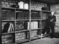 1977-3175 Dirigent Eduard Flipse in een noodruimte waar de overblijfselen van de muziekbibliotheek van het Rotterdams ...