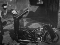 1977-3459 Een motorfiets met houtgasgenerator wordt bijgevuld.