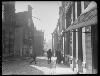 2004-2001 Mannen kijken bij een etalage van een winkel in de Voorstraat, Delfshaven. Op de voorgrond rechts een ...