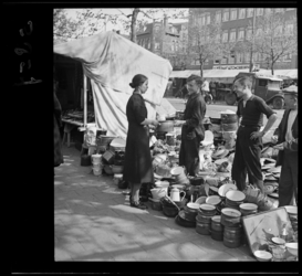5857 Drie jongens staan op een markt op de Goudsesingel bij een kraam met pannen. Een bezoeker bekijkt een pan.