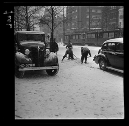 7202 Drie mannen scheppen sneeuw van de weg op de Coolsingel. Op de achtergrond een tram en hotel Atlanta.