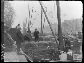 FD-3937 Met een takel lossen mannen balen hooi vanaf een vrachtschip in de Wijnhaven. Op de achtergrond meer schepen ...