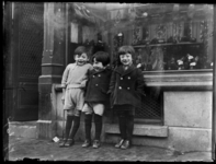 FD-3943 Drie Chinese kinderen staan voor de etalage van een schoenenwinkel, mogelijk in de Delistraat op Katendrecht.