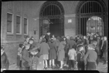 2006-15018 Een onderwijzer wacht met een groep kinderen voor de ingang van de Hudsonschool aan het Bospolderplein voor ...