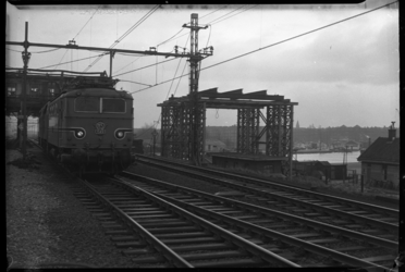 2006-16077 Een locomotief rijdt over het spoor bij de Delfshavense Schie langs het onderstel van een nieuw seinhuis. ...
