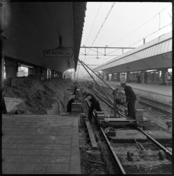 THO-1042 Met een kleine kraan op rails bouwen bouwvakkers perron 5 van het Centraal Station aan het Stationsplein.
