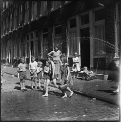 THO-1045 Op een warme dag spelen kinderen met water in de Haarlemmerstraat. Ter hoogte van nummer 141.