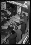 THO-1089 Klanten staan bij een tafel met stoffen tijdens een opruiming bij kledingwinkel Esders aan de Binnenweg.