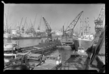 THO-1124 Drijvende kranen lossen schepen in de Merwehaven. Op de kraan rechts hangt een bord met 'NV Stuwadoorsmij. ...
