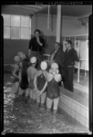 THO-1147 Een badjuffrouw staat met een microfoon bij een groepje zwemmers. Uit een serie over schoolzwemmen in het ...