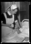 THO-1281 Een verpleegkundige staat bij het bed van een patiënt en toont de 'Tele-tracer', een nieuwe vinding waarmee ...