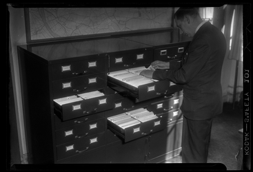 THO-1301 Op het hoofdbureau van de politie aan het Haagseveer kijkt een man in kaartenbakken. Het is een nieuw systeem ...