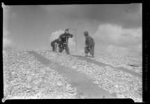 THO-1344 Drie jongens spelen met een fiets op een berg met stenen op een parkeerterrein aan de G.J. de Jonghweg.