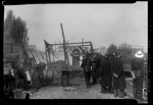THO-1459 Brandweermannen staan bij een uitgebrande loods van oud ijzer- en metaalhandelaar J.H. Fennema. De loods staat ...