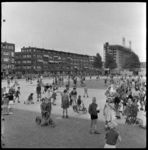 THO-1553 Met rolschaatsen en steppen spelen kinderen op de Noorderhavenkade. Op de achtergrond wordt een flat gebouwd ...