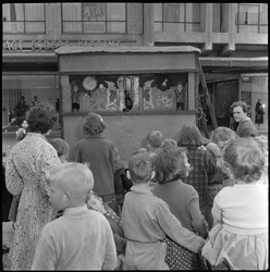 THO-1555 Kinderen kijken naar poppenkast op de Binnenweg. Op de achtergrond een winkel van Esders Kleding.