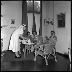 THO-1569 Een verpleegster schenkt thee voor patiënten die in de recreatiezaal zitten van het Zuiderziekenhuis aan het ...