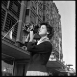 THO-1672 Actrice Ann Hasekamp fotografeert het Groothandelsgebouw met een Speed Graphic camera. Hasekamp speelt toneel ...
