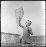 THO-1696 Een jongen speelt met een zelfgemaakte vlieger op het Grote Visserijplein. Links de Rösener Manzstraat, rechts ...