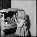 THO-1935 Een meisje staat met een brandende kaars bij een kerststal.