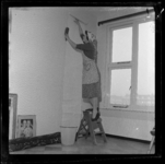 THO-2066 Een vrouw behangt een woonkamer aan de 1e Gijsingstraat.