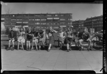 THO-207 Een groep kinderen zit op een hek op de Noorderhavenkade. Ter gelegenheid van de tiende bevrijdingsdag eten ze ...