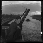 THO-3036 Een brugwachter van de Hefbrug bekijkt voorbijkomende schepen in de Koningshaven. Op de achtergrond de ...