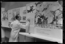 THO-304 Man in witte jas schildert teksten bij tentoonstelling over de Tweede Wereldoorlog in het gebouw van de ...
