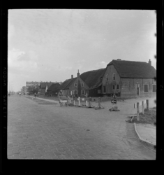 THO-3121 Een vrouw loopt met kinderwagen langs de afgesloten Dorpsweg. De boerderij op de hoek met de Slinge (links) ...